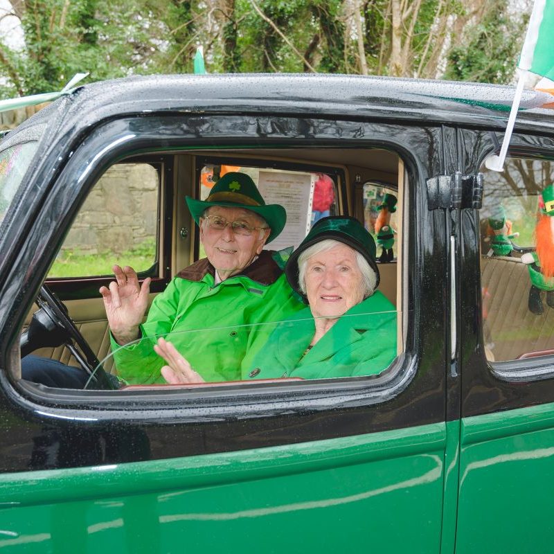 Older man and woman sitting in car dressed in all green