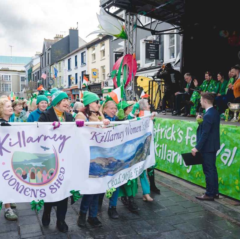 group of women walking in parade holding Killarney's Women's Shed sign